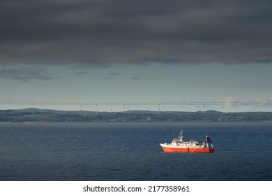 Small Fishing Ship With Red Hull In The Ocean. Galway Bay, Ireland. Food Industry And Supply Concept. Cloudy Sky And Dark Color Water Surface.