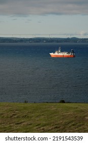 Small Fishing Ship With Red Hull In The Ocean. Galway Bay, Ireland. Food Industry And Supply Concept. Cloudy Sky And Dark Color Water Surface.