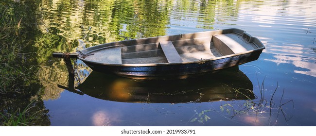 Small Fishing Tin Boat With Wooden Skin Moored On Lake Coast Close Up Side View