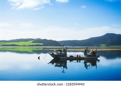 Small Fishing Trawler Moored In Perfectly Calm Waters. Lush Green Of Distant Mountain On The Other Side Of The Bay. Quiet Morning In Far North, New Zealand