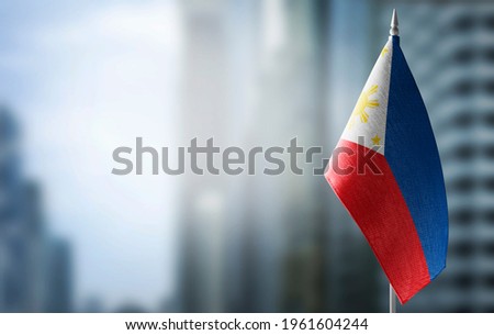 A small flag of Philippines on the background of a blurred background