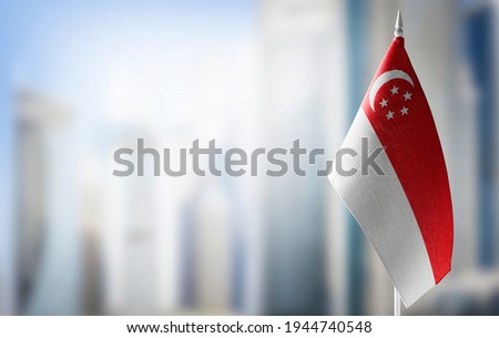 A small flag of Singapore on the background of a blurred background