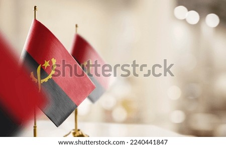 Small flags of the Angola on an abstract blurry background