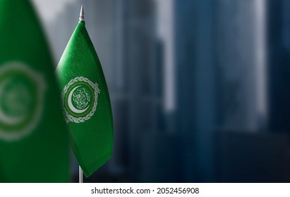 Small flags of Arab League on a blurry background of the city