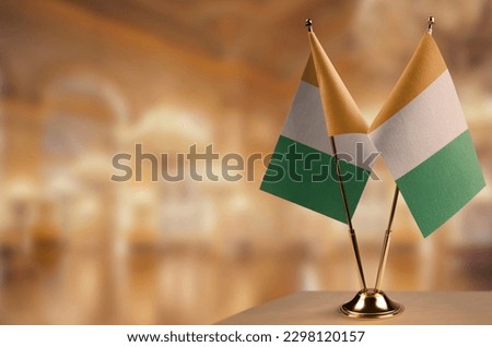 Small flags of the Cote dIvoire on an abstract blurry background.