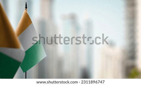 Small flags of the Cote dIvoire on an abstract blurry background.