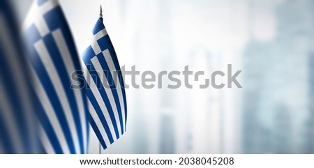 Small flags of Greece on a blurry background of the city