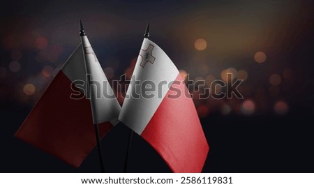 Small flags of the Malta on an abstract blurry background.