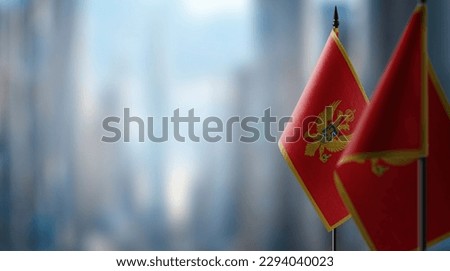 Small flags of the Montenegro on an abstract blurry background.
