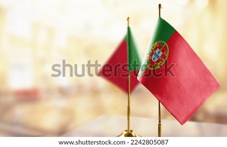 Small flags of the Portugal on an abstract blurry background.