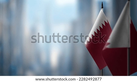 Small flags of the Qatar on an abstract blurry background.