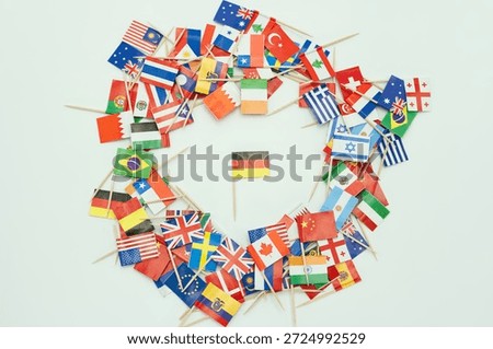 Small flags representing different countries are arranged in a circle. The German flag is placed in the center of the display, highlighting the theme of global diversity.