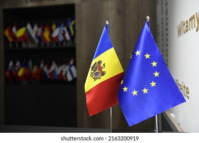 Small flags of Republic of Moldova and European Union on flagpole in foreground with multiple other small flags in background. Concept of EU perspective for Modova. 