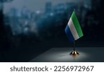 Small flags of the Sierra Leone on an abstract blurry background.