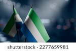 Small flags of the Sierra Leone on an abstract blurry background.