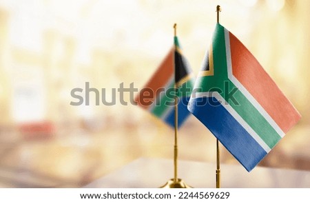 Small flags of the South Africa on an abstract blurry background.