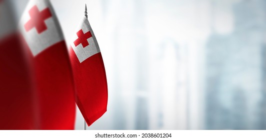 Small Flags Of Tonga On A Blurry Background Of The City