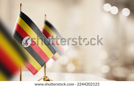 Small flags of the Uganda on an abstract blurry background.