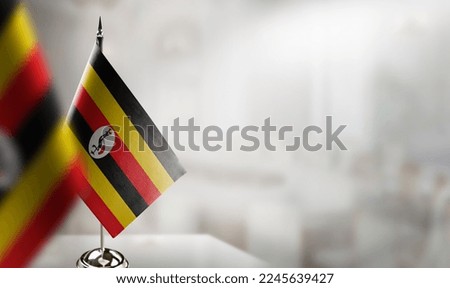 Small flags of the Uganda on an abstract blurry background.