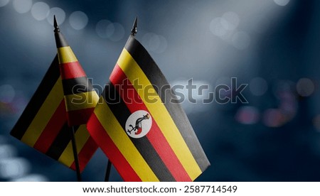 Small flags of the Uganda on an abstract blurry background.