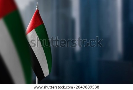 Small flags of United Arab Emirates on a blurry background of the city