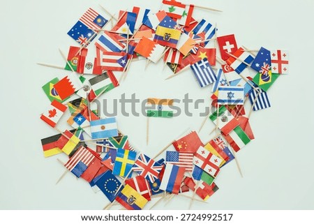 Small flags from various countries are placed in a circular design on a light background. The flag of India is positioned in the center surrounded by other flags.