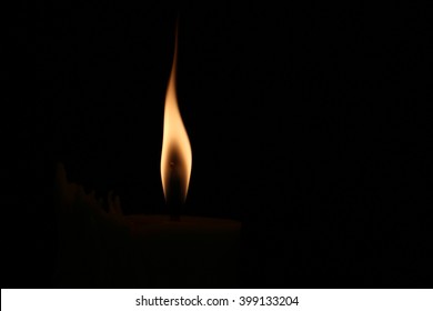 A Small Flame On A Dark Black Background.