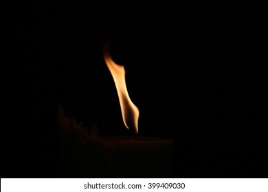 A Small Flame On A Dark Black Background.