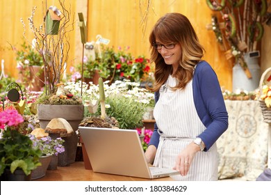 Small Flower Shop Owner Working On Laptop In Her Shop.