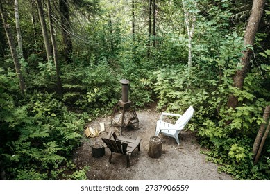 Small forest seating area with fire pit surrounded by dense woodland near Saguenay, Quebec