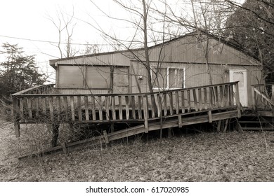 Small Forgotten And Neglected House With A Collapsing Porch. Slight Sepia Tone. Winter Season. 