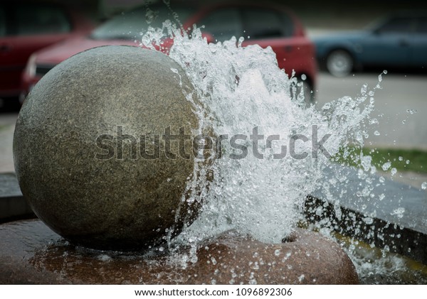 small
fountain with water splashes and round big
stone