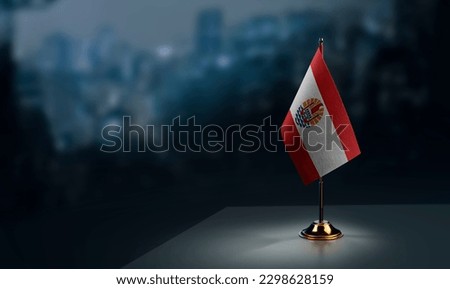 A small French Polynesia flag on an abstract blurry background.