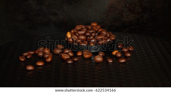 Small fried coffee\
beans from a package in a plastic lens cover and scattered side by\
side on a stand