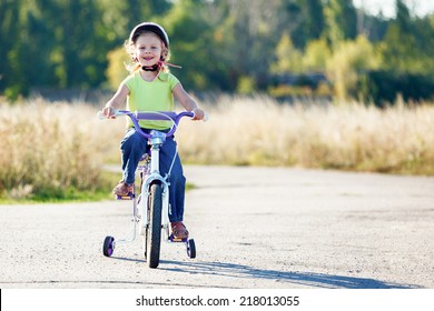 Small Funny Kid Riding Bike With Training Wheels.