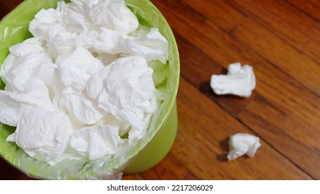 A Small Garbage Bin Full With Used Tissue Paper, On A Wooden Floor.