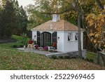 Small garden house, she-shed with a golden retriever dog looking out on a beautiful fall day. 