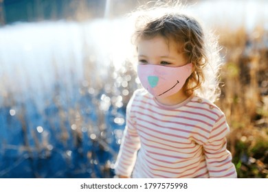 Small girl with face mask outdoors in nature, walking. - Powered by Shutterstock