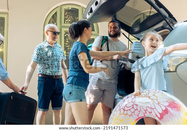 Small girl\
going to sea with family, preparing car trunk with baggage and\
luggage bags to travel to seaside destination during summer. People\
using automobile and trolley to leave on\
trip.