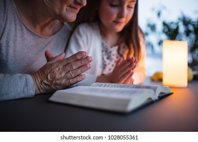 A small girl and grandmother praying at home.