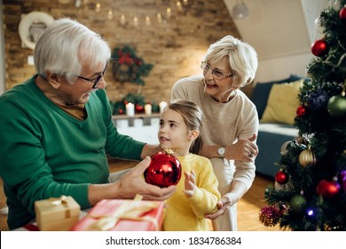 Small girl and her grandparents talking while decorating Christmas tree at home. - Powered by Shutterstock