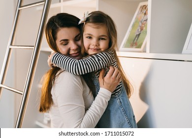 Small Girl Hugging Her Mom Standing Near Book Case