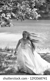 Small Girl Kid With Long Blonde Hair And Pretty Smiling Happy Face In Prom Princess White Dress Standing Sunny Day Outdoor Near Water