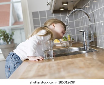 Small Girl In The Kitchen Drinking Water