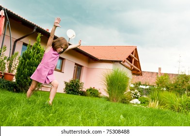 Small Girl Making Cartwheel On Garden With Family House In Background