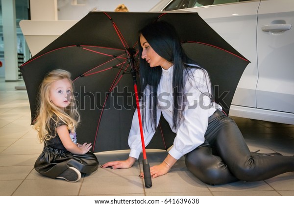 Small girl and\
mom in exhibition hall for\
car