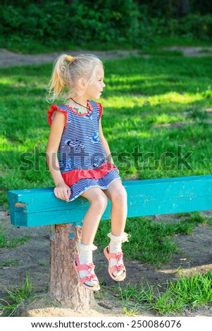 Small girl on bench in summer blossoming garden.
