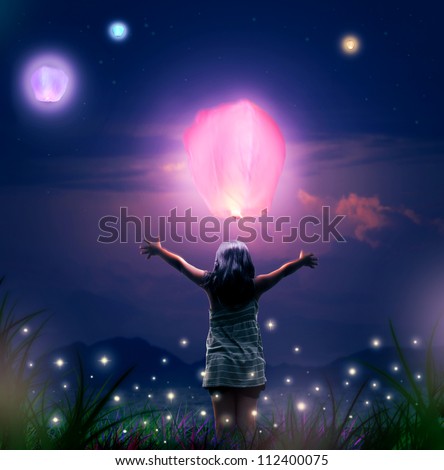 Small Girl Releases a Glowing  Sky Lantern Up on a Night Sky. Fantasy Scene and Lantern Festival like in Chiang Mai, Thailand. It can bealso about Healing, Solitude and Condolences Theme.