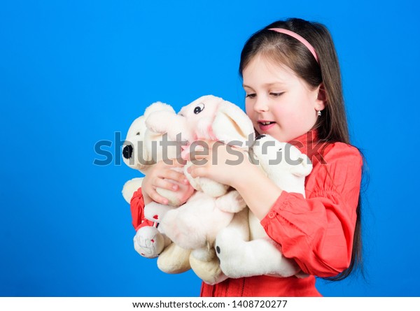 Small girl smiling face with toys. Happy childhood. Little girl play with soft toy teddy bear. Lot of toys in her hands. Collecting toys hobby. Cherishing memories of childhood. Childhood concept.
