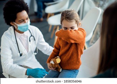 Small girl sneezing into elbow in a waiting room at the hospital during coronavirus pandemic.  - Powered by Shutterstock